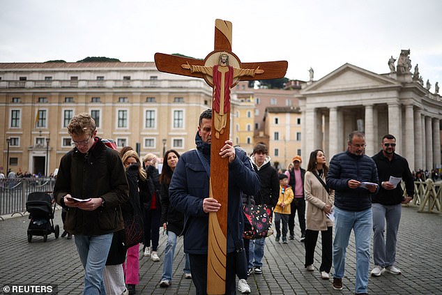 Ένας προσκυνητής κουβαλά έναν σταυρό καθώς ο Πάπας Φραγκίσκος εισήχθη για να συνεχίσει τη θεραπεία για λοίμωξη του αναπνευστικού, στην πλατεία του Αγίου Πέτρου, στο Βατικανό, σήμερα